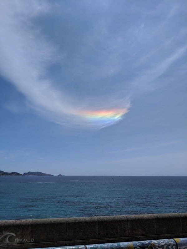 Tenues nubes sobre el mar.  Una línea de colores del arcoíris en ellos, con azul en la parte inferior y rojo en la parte superior.