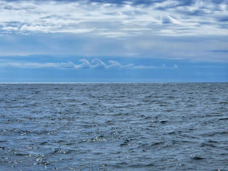 Una línea de nubes ondulantes sobre el mar.